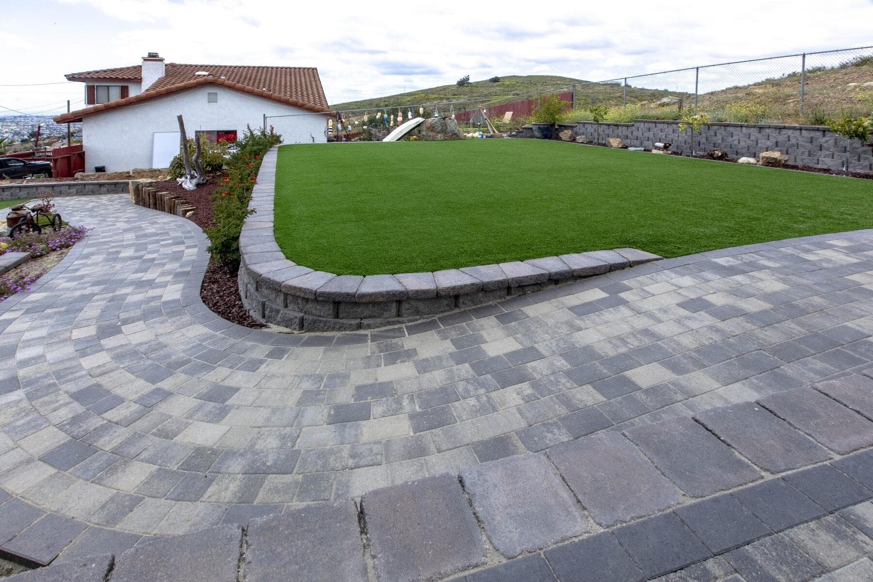 Wide view of the curved paver patio and turf lawn at Dictionary Hill