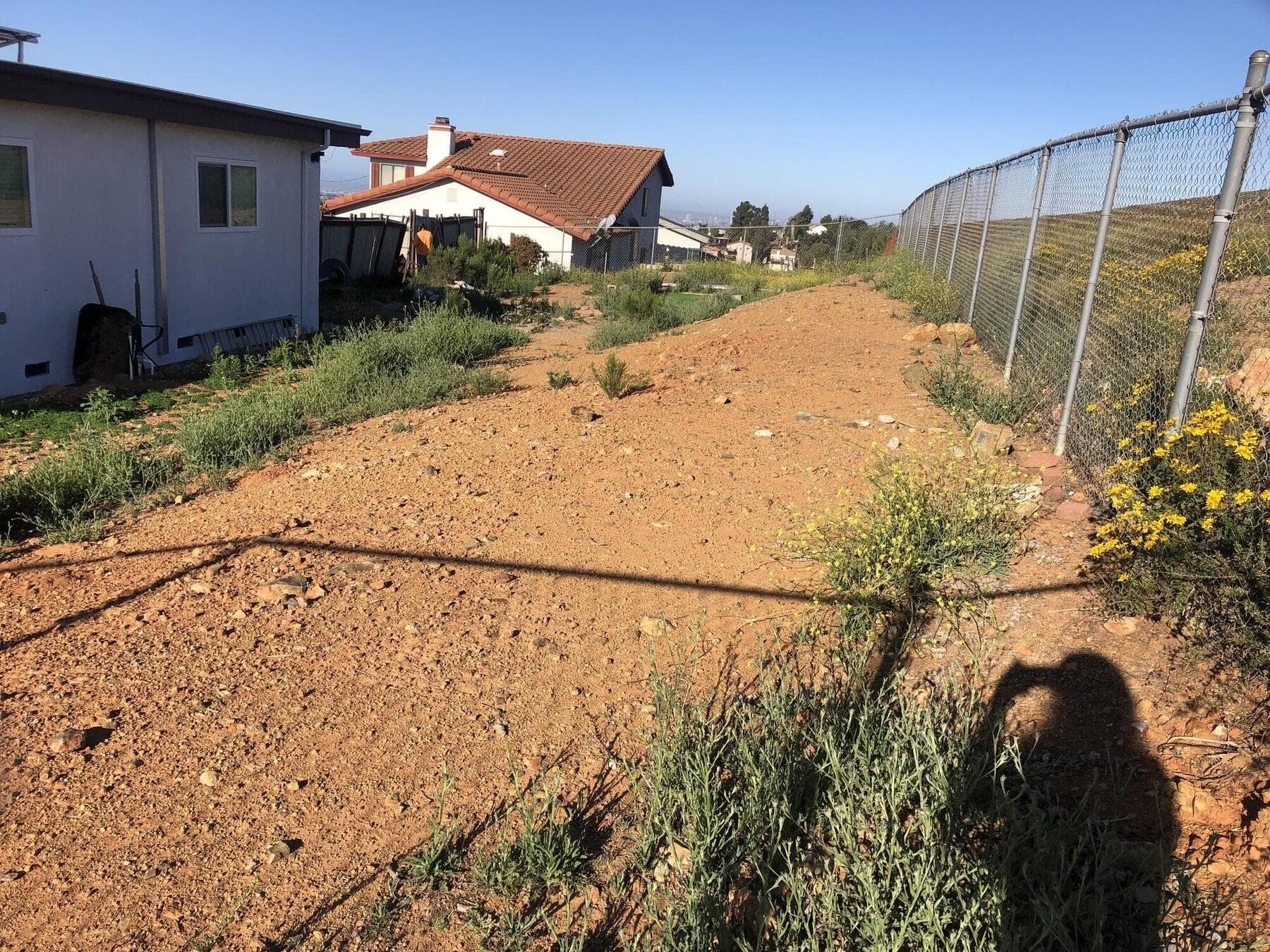 Unused dirt slope along the fence at Dictionary Hill before grading and pavers