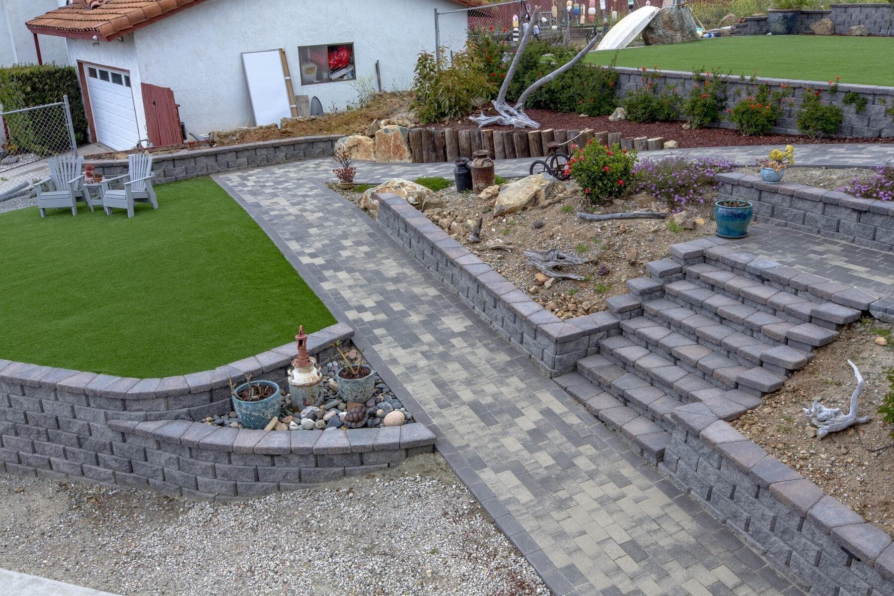 Hillside levels with paver walk, stairs, turf, and retaining walls