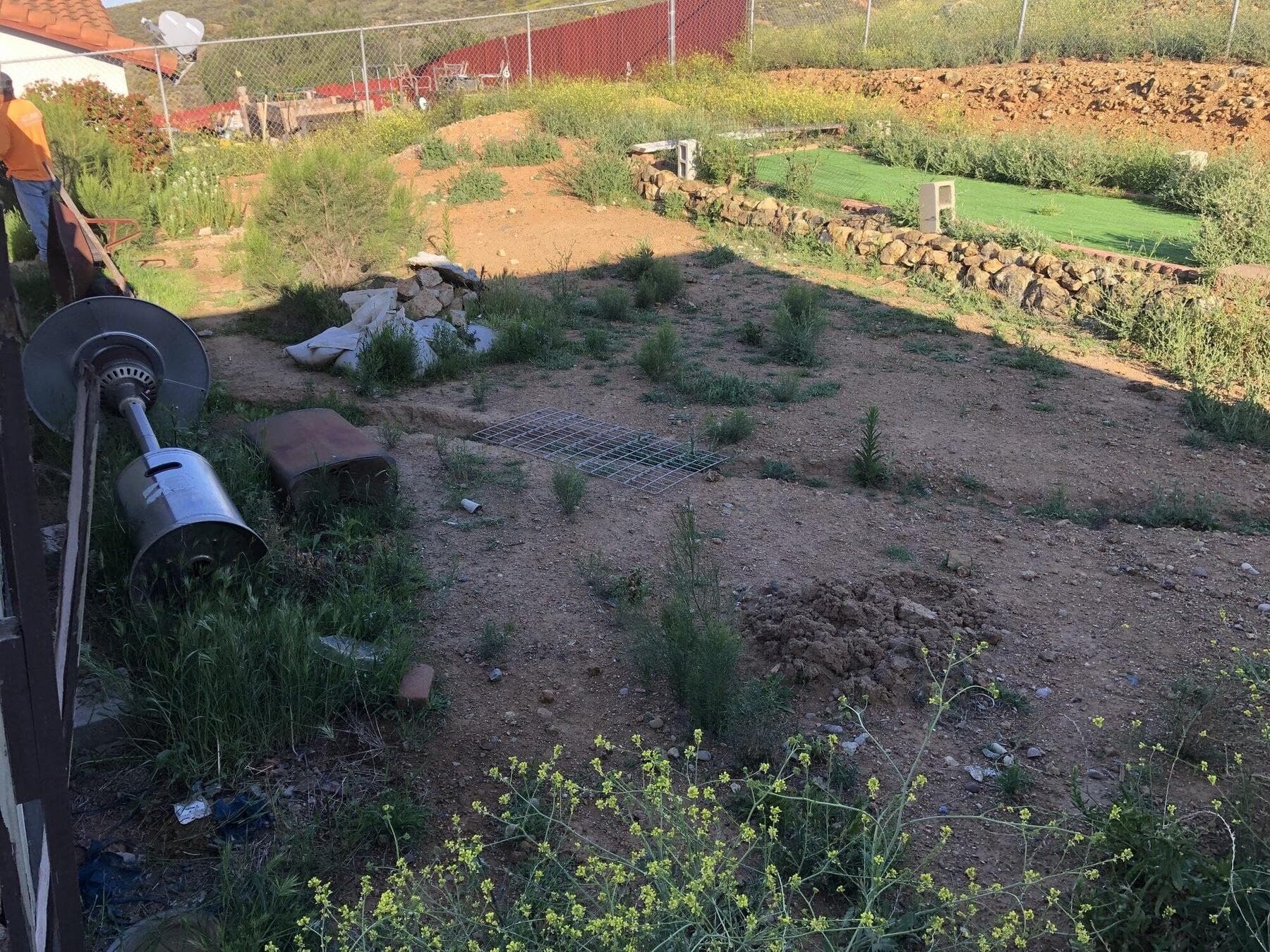 Overgrown dirt yard and leftover stone on the Dictionary Hill hillside before work started