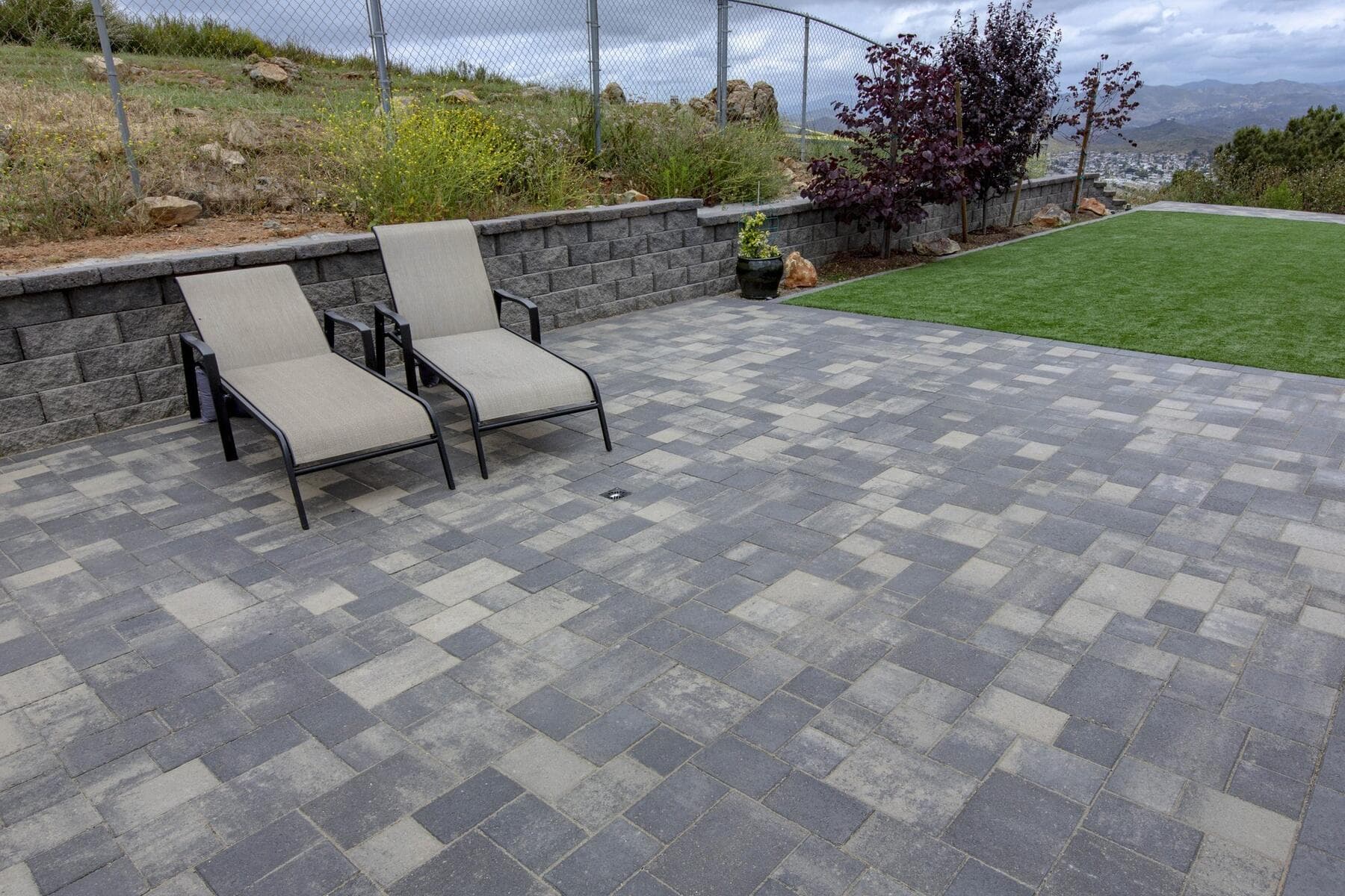 Lounge chairs on the finished paver patio beside the turf