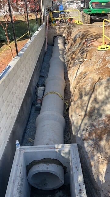 RCP pipe in a gravel trench beside a block wall in El Cajon