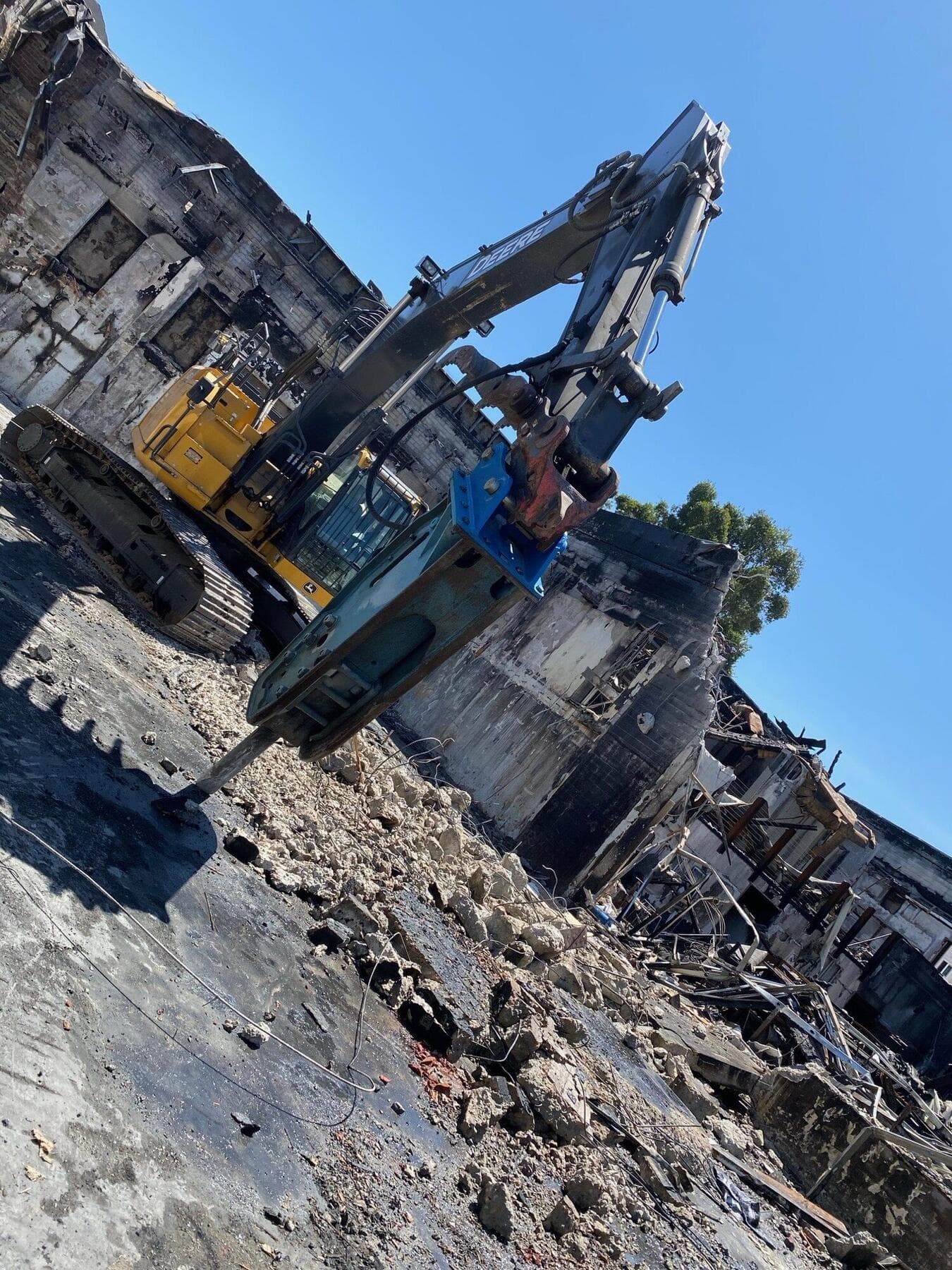 Deere excavator with a breaker on a burned commercial building in La Mesa