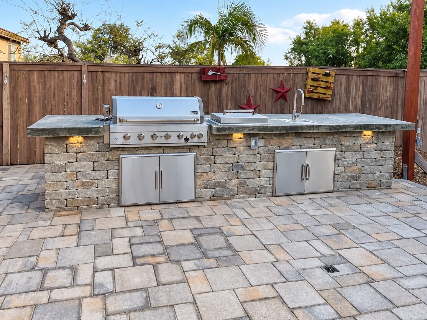 Outdoor kitchen island with grill, sink, and under-counter lights