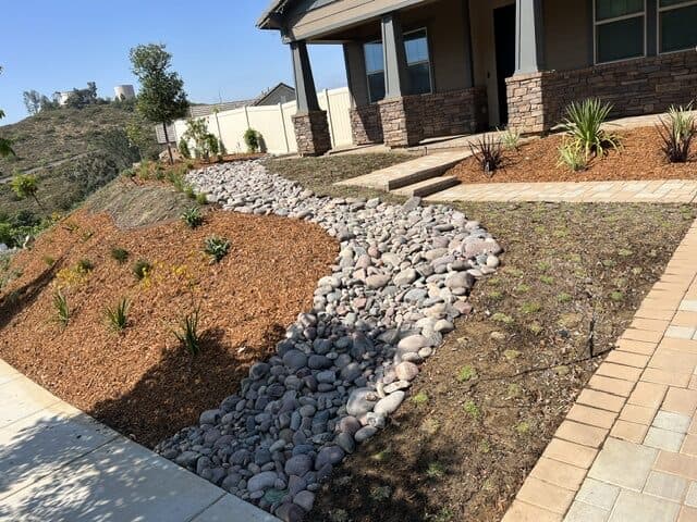 River-rock swale and planting at the front of the Poway house