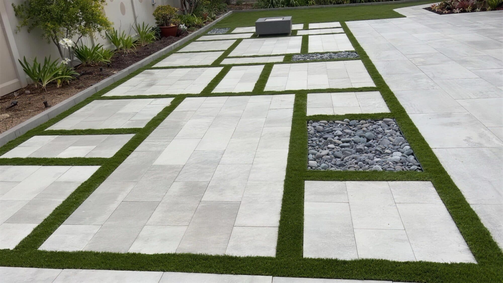 Durafusion slab field with turf joints, river-rock panels, and a fire table