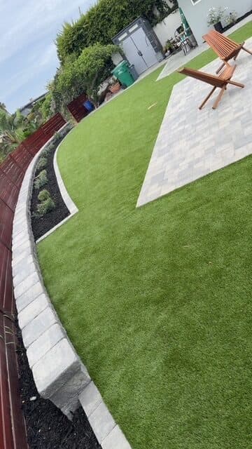 Block seating wall, turf, and paver patio from along the wall