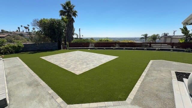 Square paver patio in turf with palms and a coastal view
