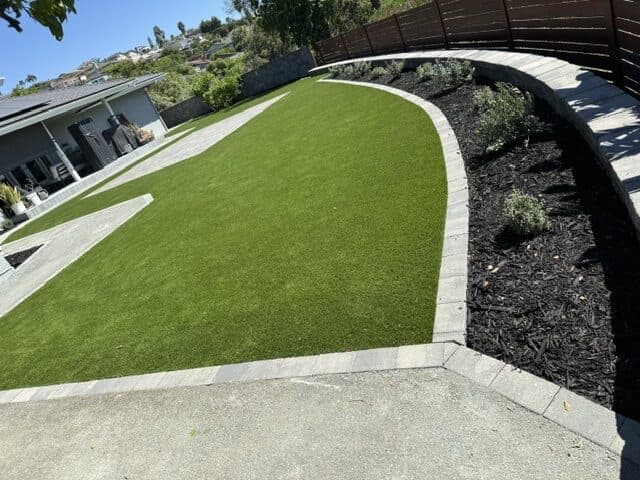 Curved seating wall, planting bed, turf, and paver patio in Sunset Cliffs