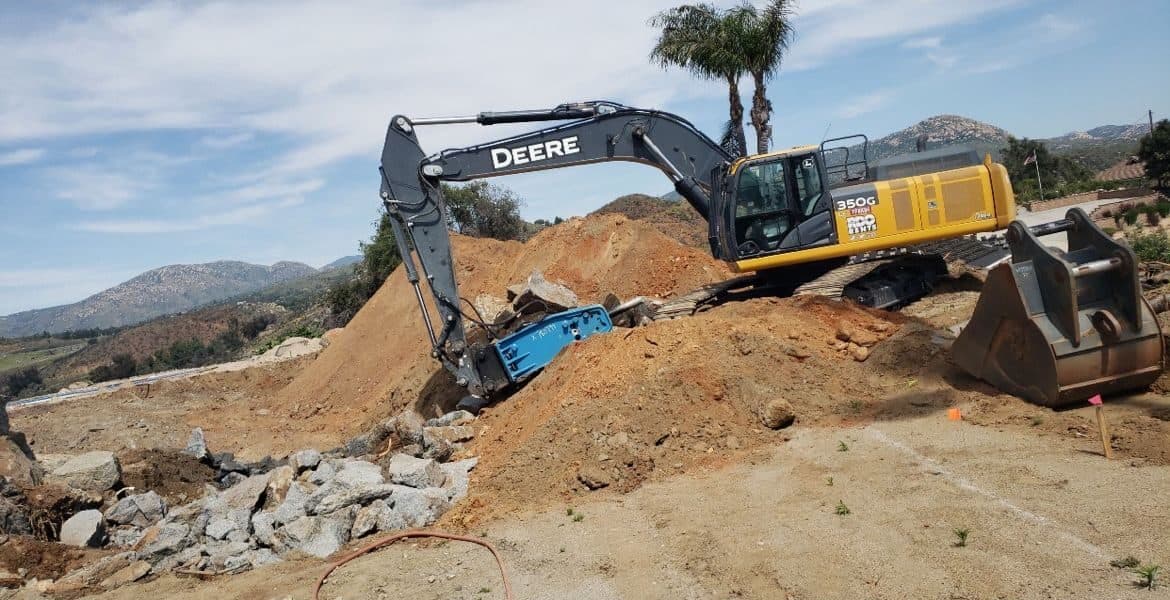 Deere 350G excavator breaking rock on a graded East County site