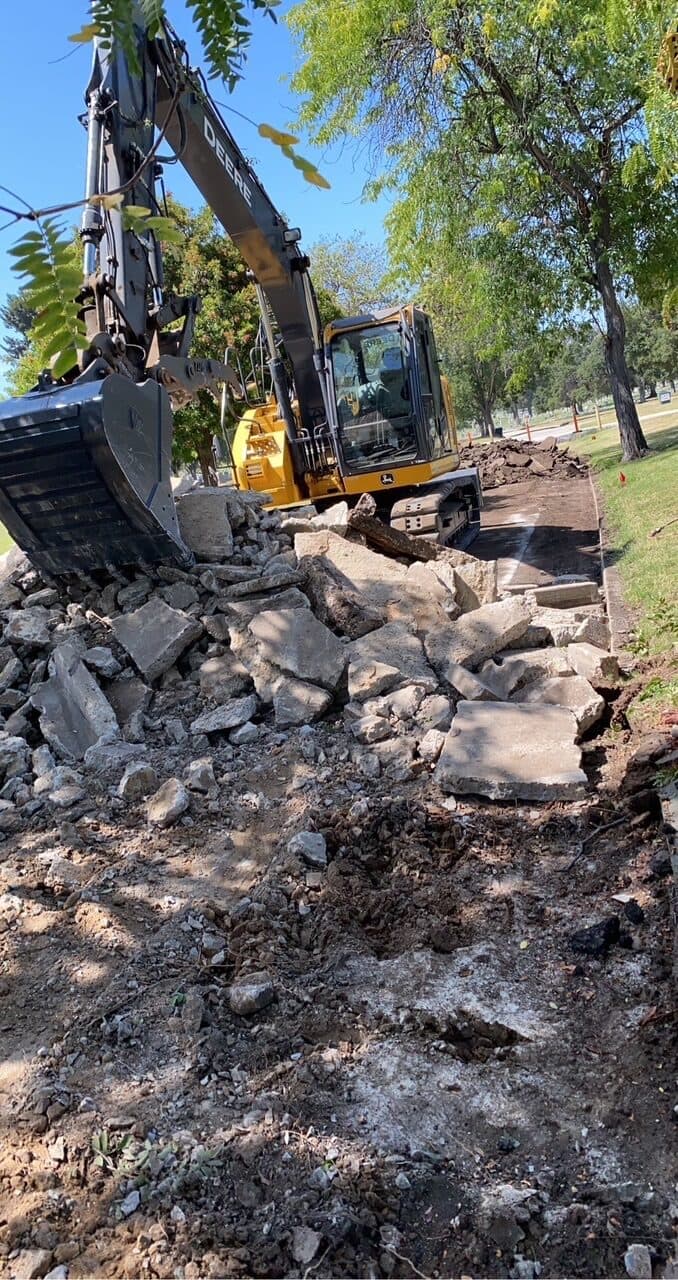 Deere excavator breaking out a concrete sidewalk