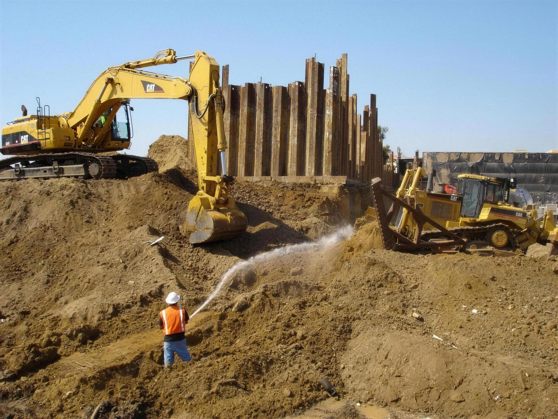 Excavator and dozer on a commercial earthwork site with dust control